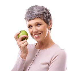 senior woman smiling and holding a green apple