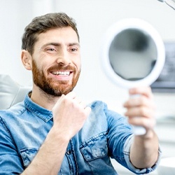 dental patient admiring his smile in a mirror