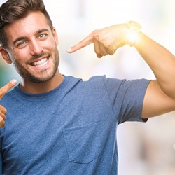 young man pointing to his smile with dental implants in Sagamore Hills