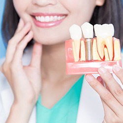 dentist holding a dental implant model