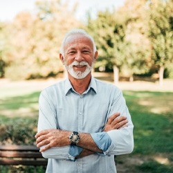 Senior man with watch standing outside smiling 