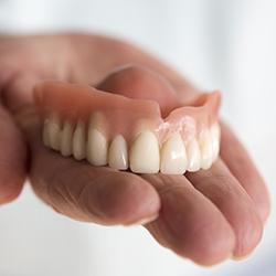 Hand holding a full denture