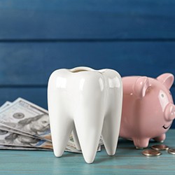 a model of a porcelain tooth and piggy bank and money