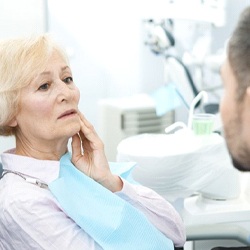 senior woman with mouth pain talking to her dentist about failed dental implants in Sagamore Hills