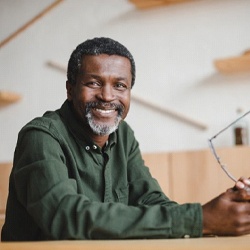 senior man sitting at a desk and holding his glasses in his hands