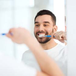 man brushing his teeth in front of a mirror