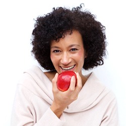 Woman with dental implants in Sagamore Hills eating an apple