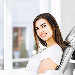 Woman in white shirt sitting in dental chair and smiling