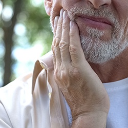 Close-up of bearded man rubbing his jaw in pain