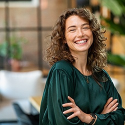 Woman in green shirt smiling with arms folded