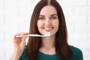 Woman with brown hair brush her teeth