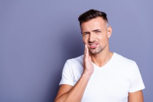 Man with hand on cheek due to dental pain