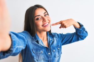 Woman pointing to her beautiful smile