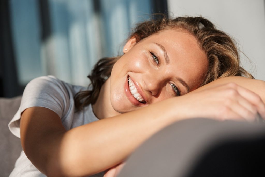 Woman with dental crown smiling on couch