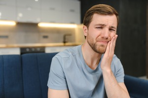 Man sitting on couch with tooth pain