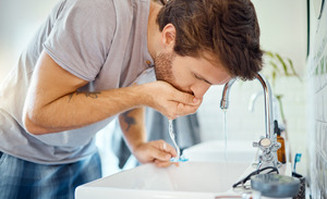 Man rinsing mouth with water after brushing teeth